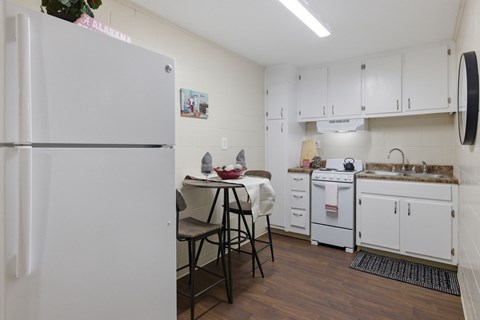A kitchen with white cabinets and a white refrigerator.