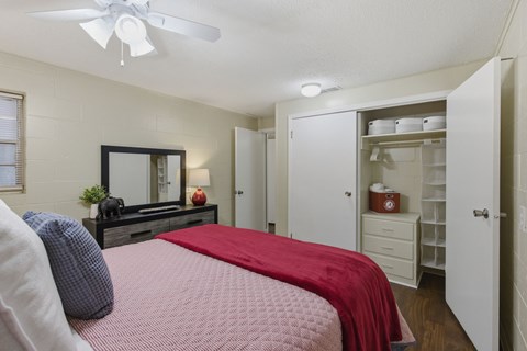 A bedroom with a bed, dresser, and a ceiling fan.
