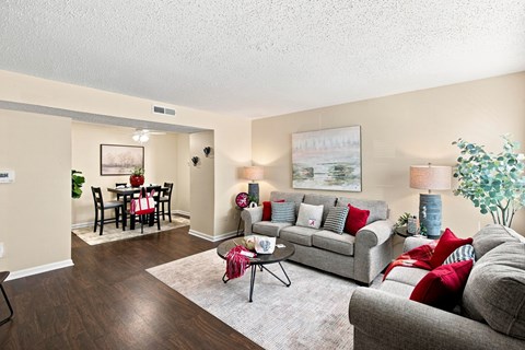A living room with a grey couch, a coffee table, a dining table with chairs, and a painting on the wall.