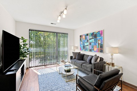 A living room with a black couch, a television, and a painting on the wall.