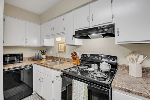 A kitchen with a black stove top oven and white cabinets.