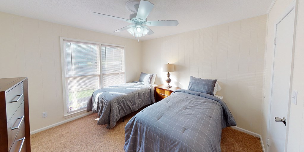 a bedroom with two beds and a ceiling fan