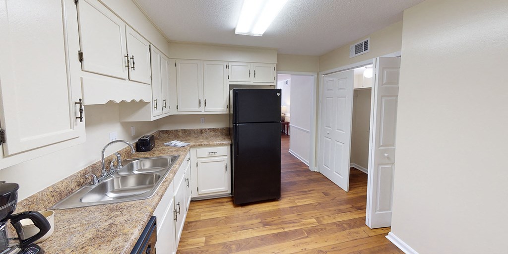 a kitchen with white cabinets and a black refrigerator