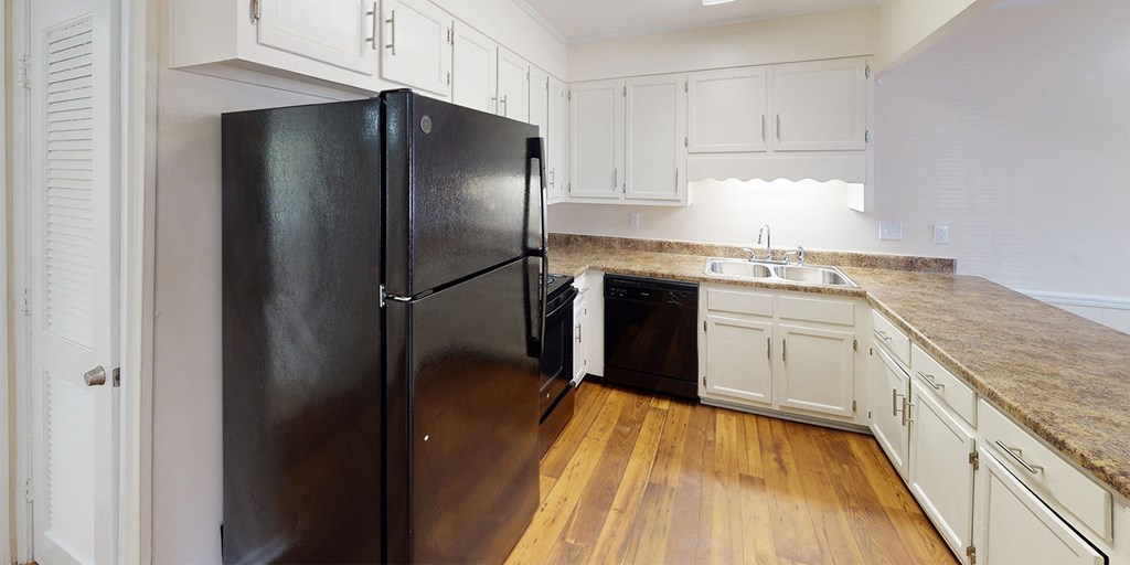 a kitchen with white cabinets and a black refrigerator