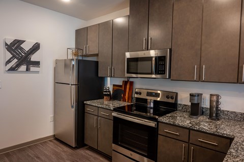 A modern kitchen with dark brown cabinets and stainless steel appliances.