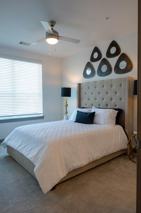 A bedroom with a large bed and a ceiling fan.