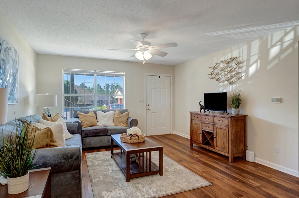 A living room with a grey couch, a wooden coffee table, and a flat screen TV on a wooden cabinet.