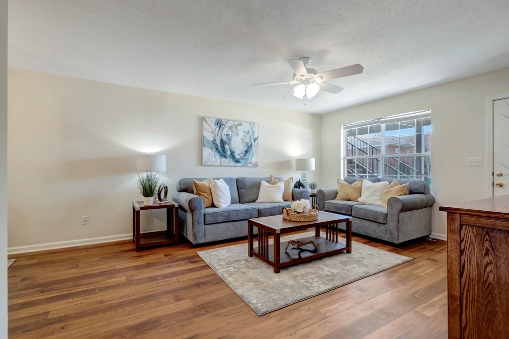 A living room with a grey couch, a coffee table, and a painting on the wall.