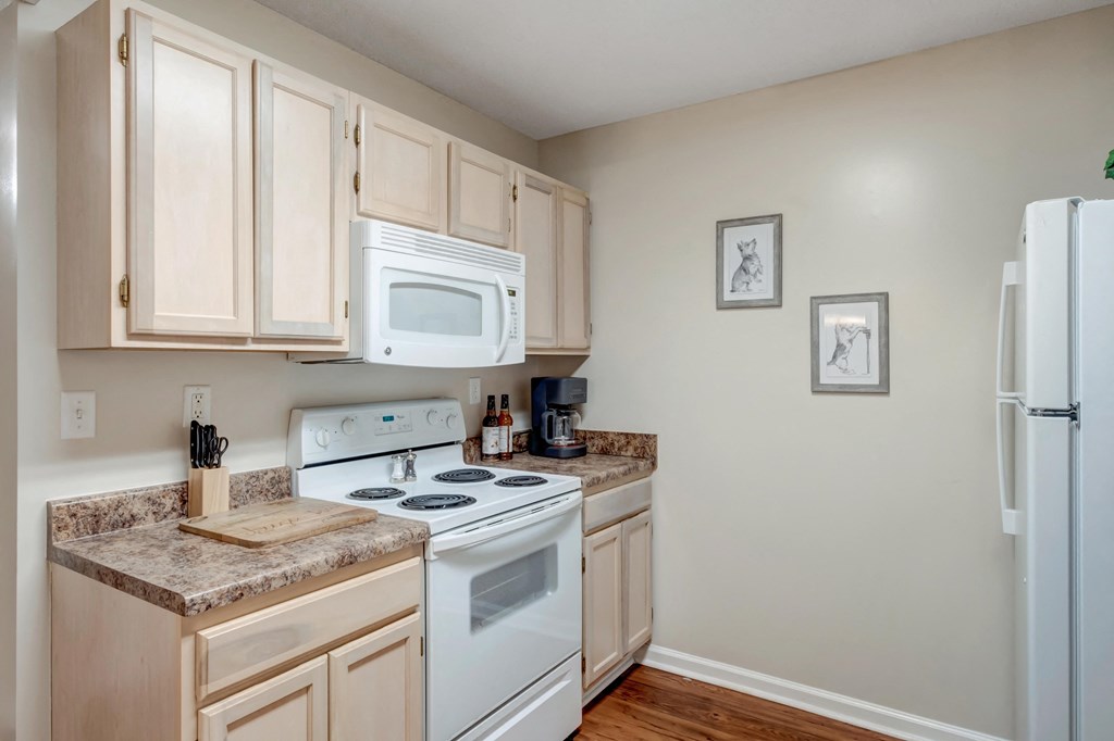 A kitchen with a white stove and white microwave.