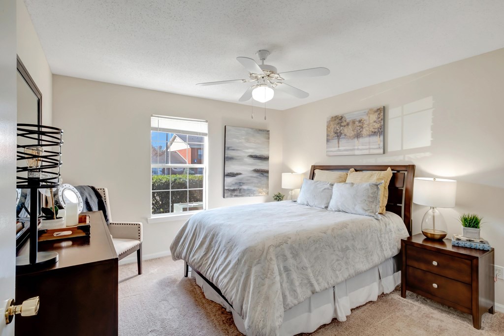 A bedroom with a large bed, a dresser, and a ceiling fan.