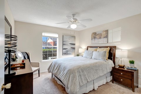 A bedroom with a large bed, a dresser, and a ceiling fan.