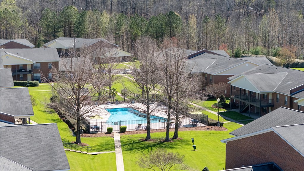 A swimming pool is surrounded by houses and trees.