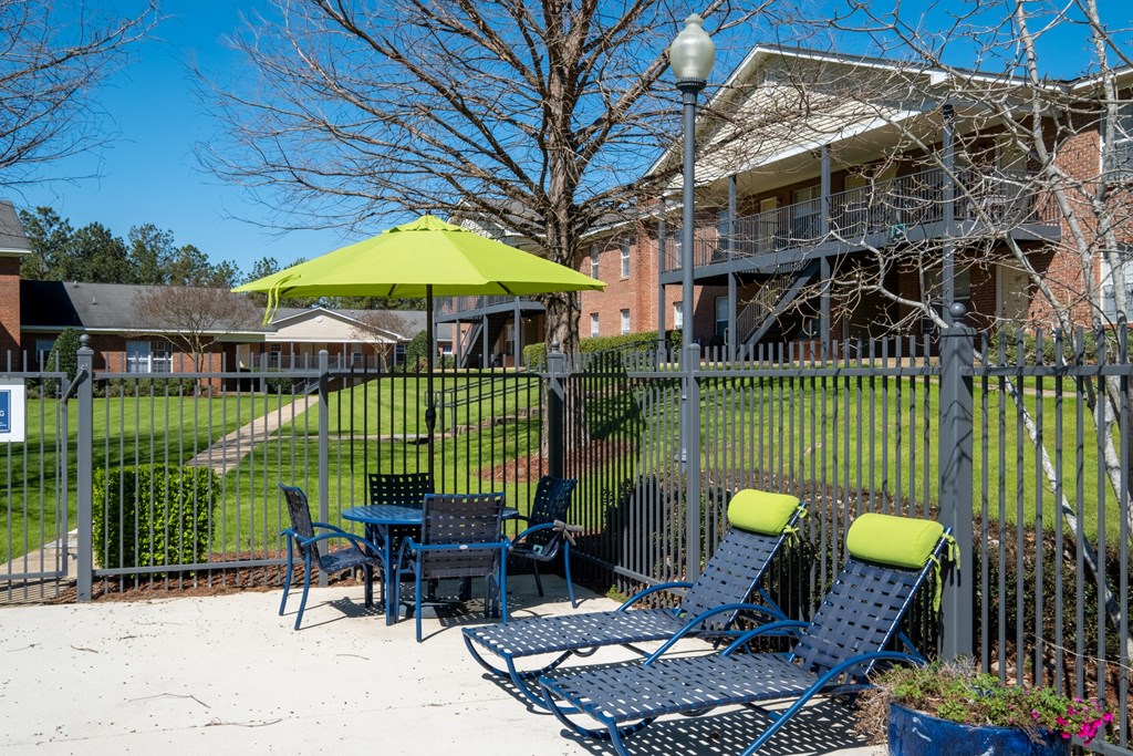 A patio with a table and chairs and a green umbrella.