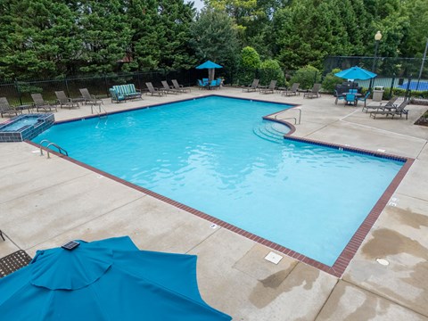 a swimming pool with blue umbrellas and chairs around it