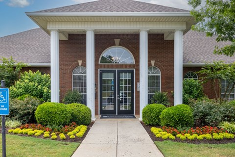 the front entrance of a brick building with columns and a porch