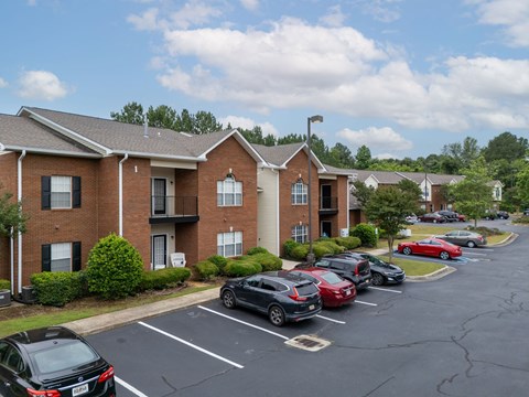 a parking lot in front of a brick apartment building with cars parked in front