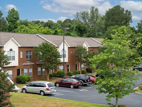 a parking lot in front of an apartment building with cars parked in the parking lot