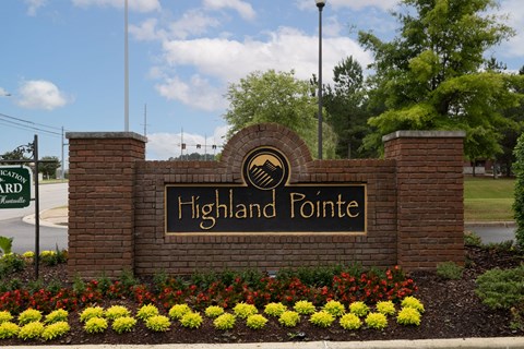 the sign for highland pointe in front of a brick wall with flowers