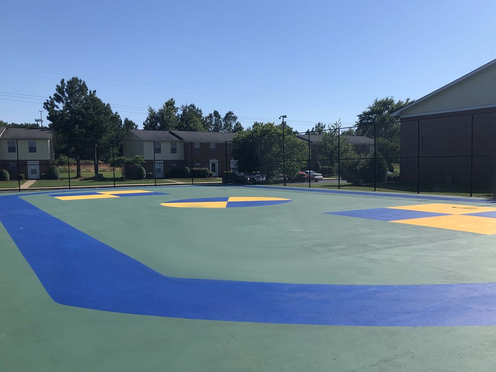 a basketball court with blue and yellow paint on it in front of houses