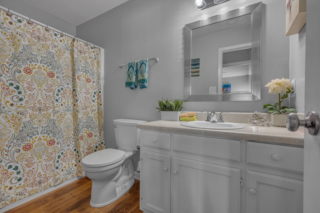 A white bathroom with a floral shower curtain.