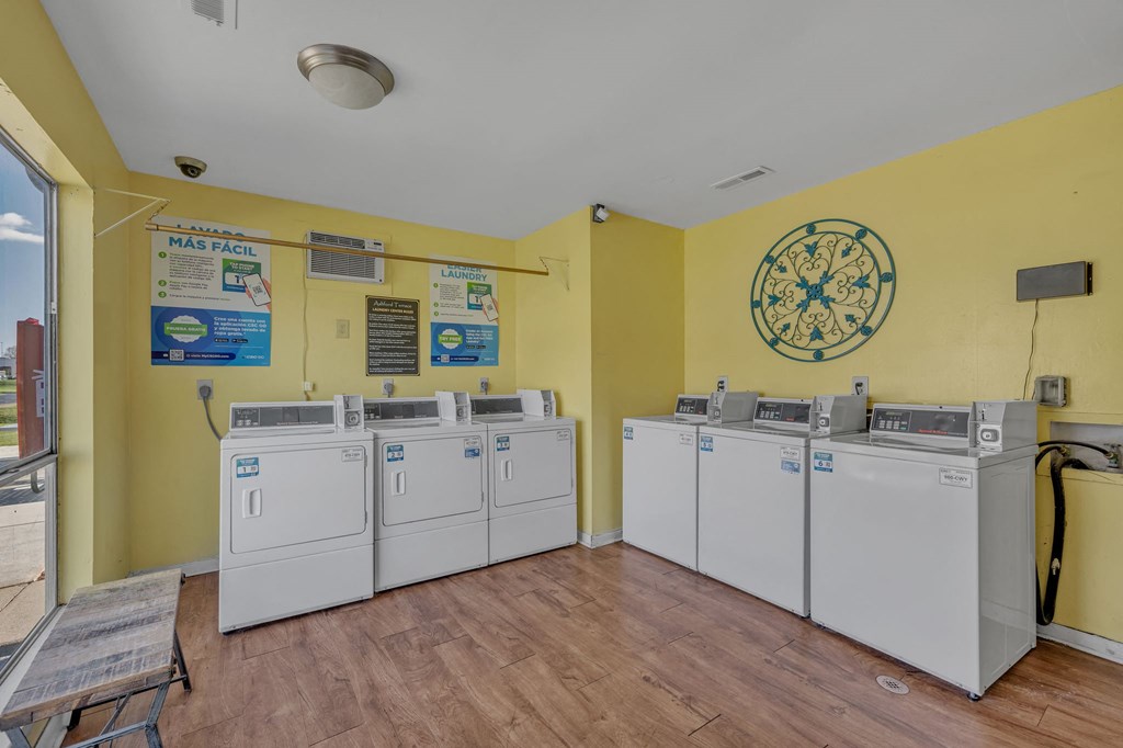 A yellow wall with a clock and washing machines.