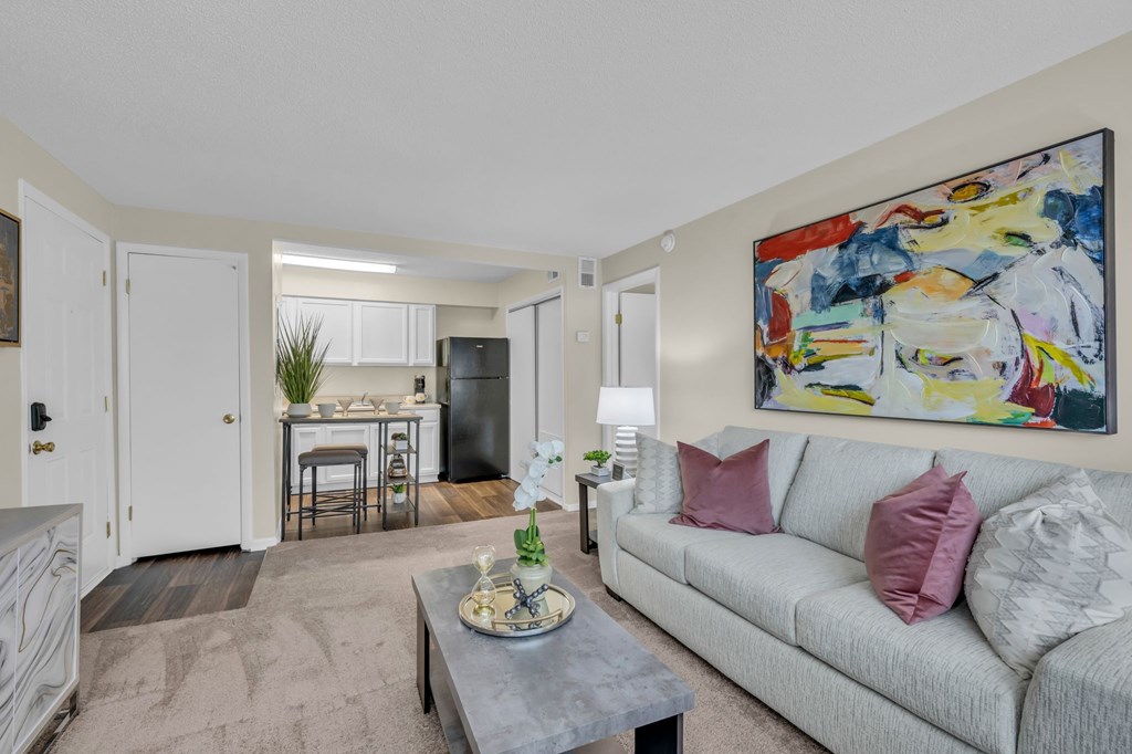 A living room with a grey couch and a painting on the wall.