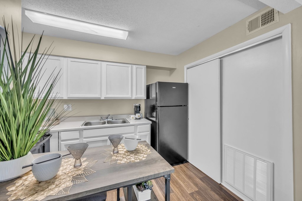 A kitchen with a black refrigerator and white cabinets.