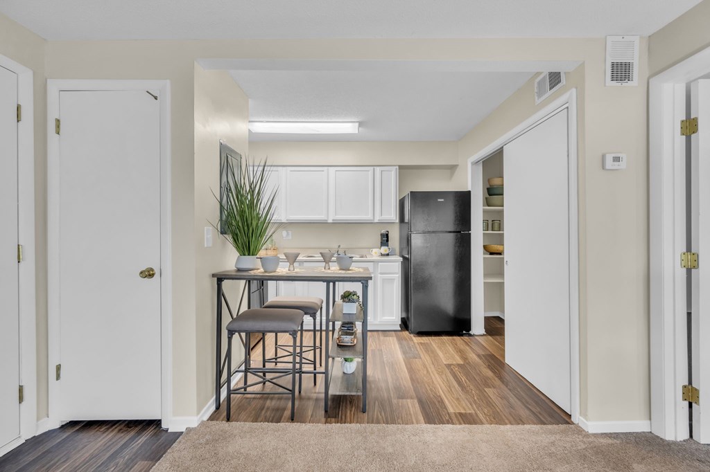 A kitchen with white cabinets and a black fridge.