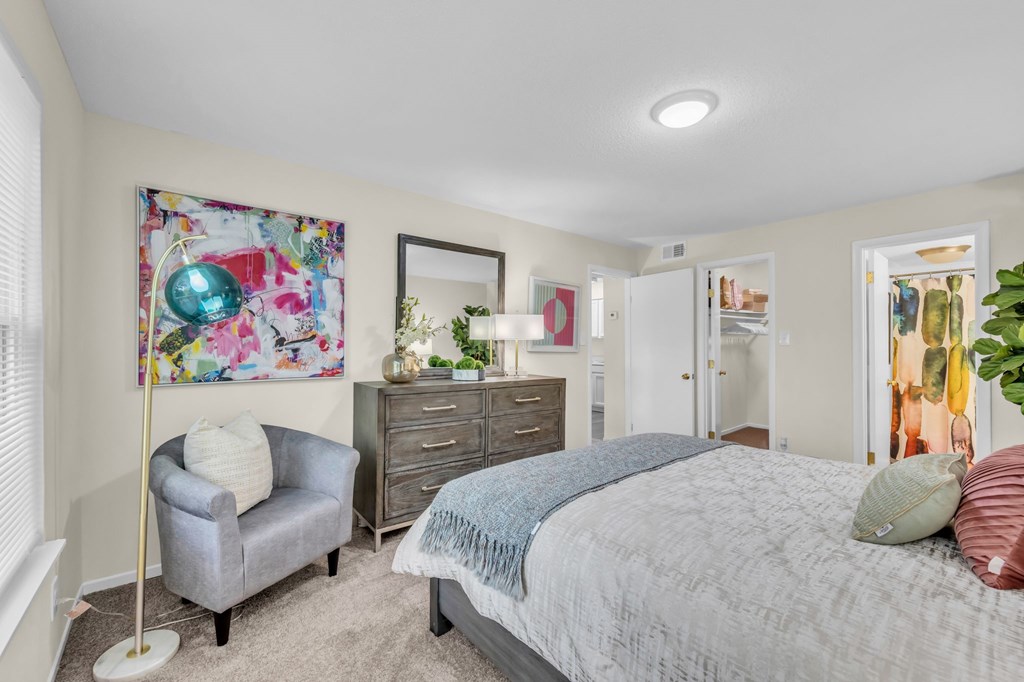 A bedroom with a bed, dresser, and chair.