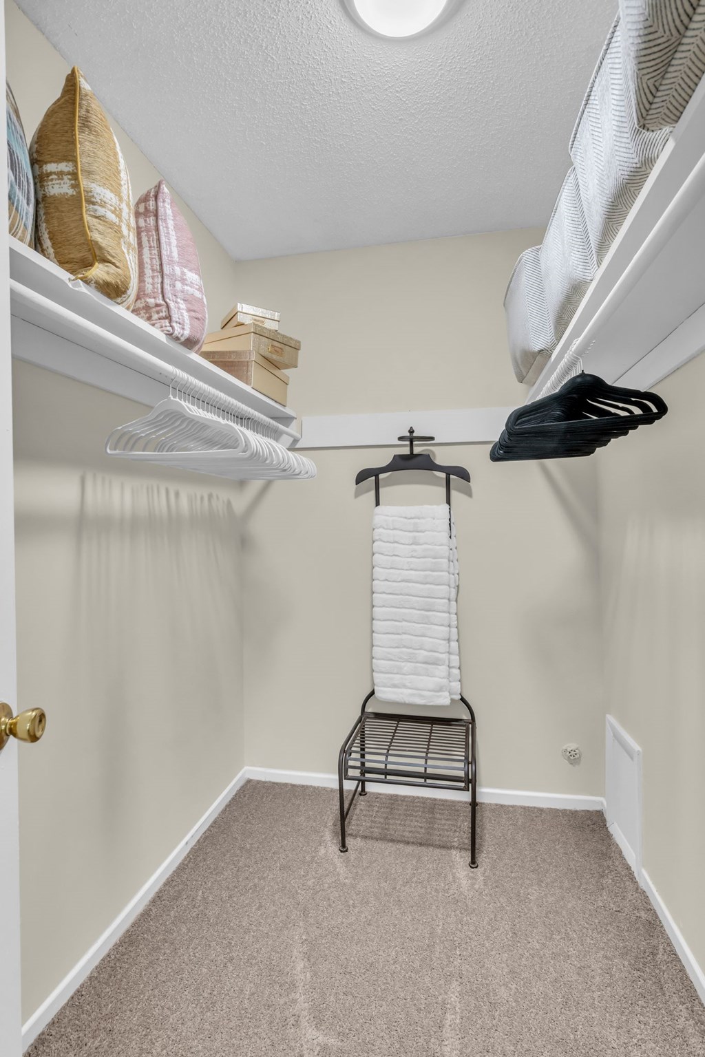 A small room with a hanging clothes rack and a carpeted floor.