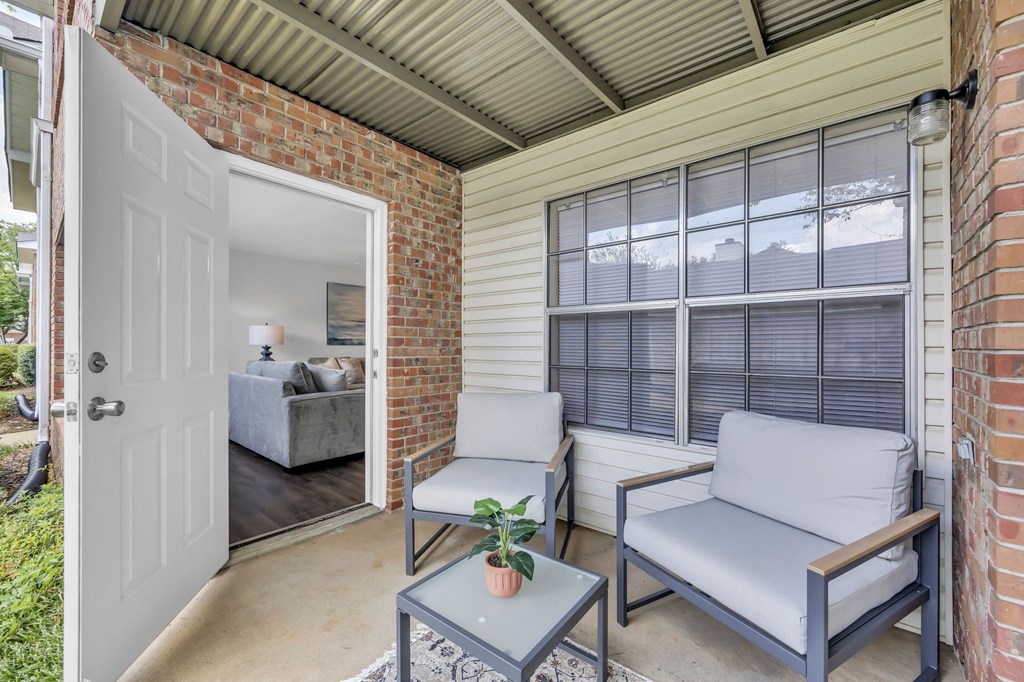 a patio with two chairs and a door to a living room
