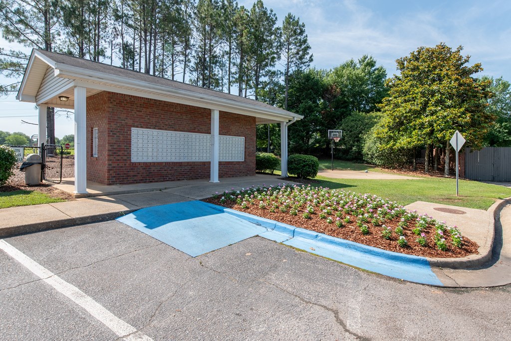 the entrance to a parking lot with a brick building and a blue handicapped ramp