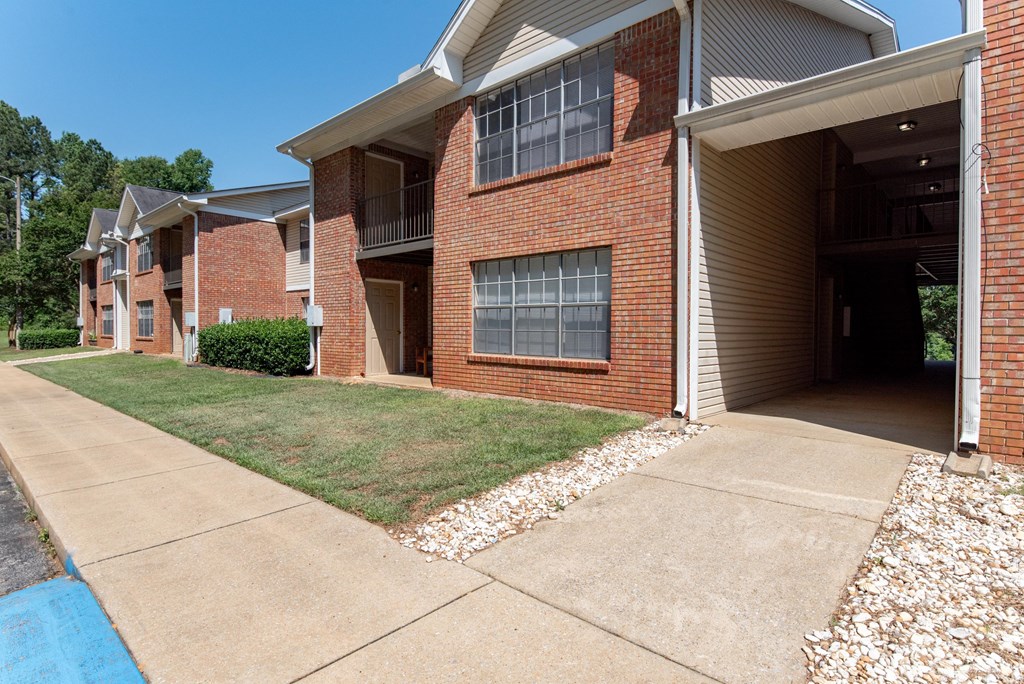 the view of a brick apartment building with a sidewalk and grass