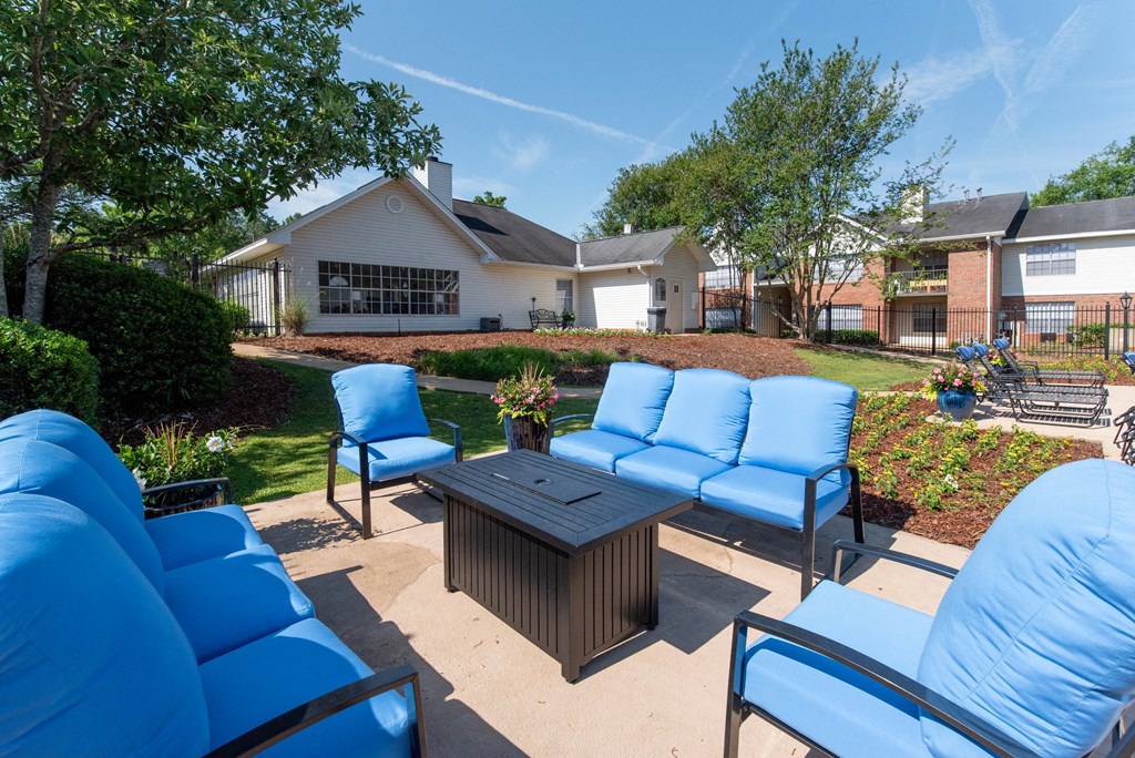 a patio with blue chairs and a table in front of a house