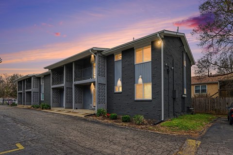 A grey building with a parking lot in front of it.