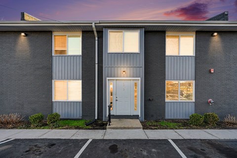 A grey building with a white door and windows.