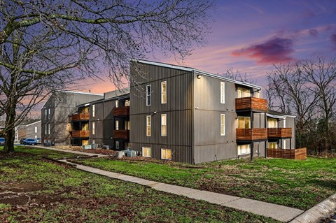 A modern apartment building with a grassy area in front.