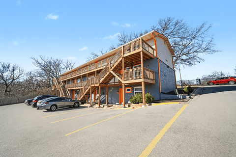 A large two-story building with a balcony and a car parked in front.