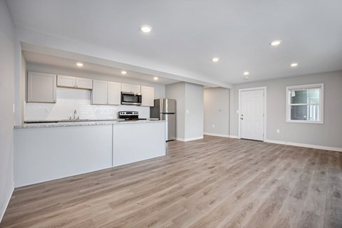 A kitchen with white cabinets and a wooden floor.