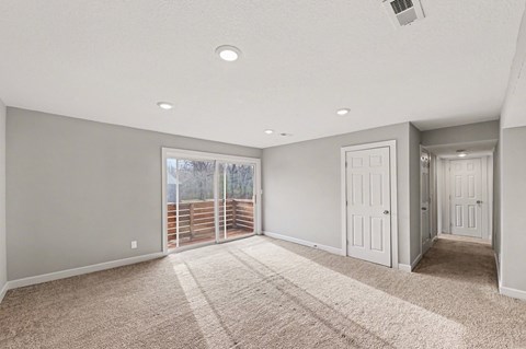 A spacious room with a carpeted floor and sliding glass doors.