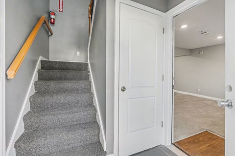 A hallway with a staircase and a door.