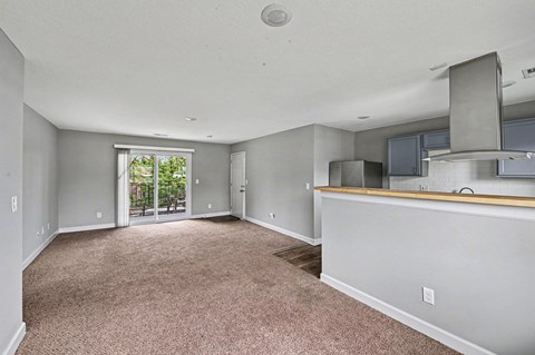 A spacious living room with a carpeted floor and a bar area.