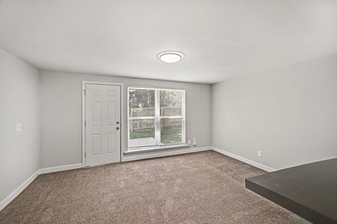 A room with a carpeted floor and a sliding glass door leading to a backyard.