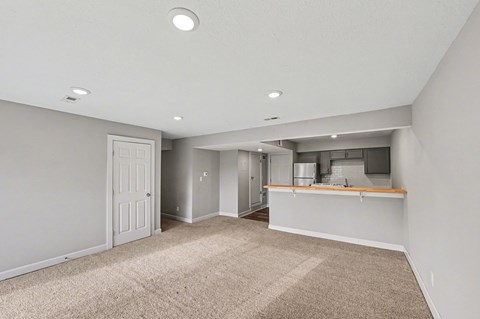 A spacious room with a kitchenette and a door leading to another room.
