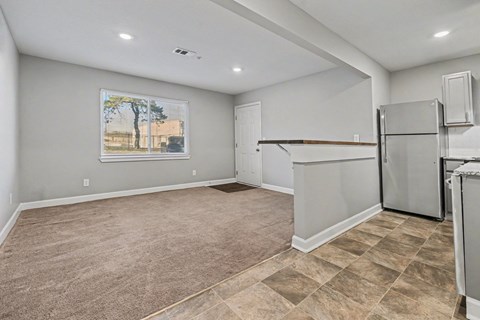A spacious kitchen with a refrigerator and a painting of a tree on the wall.