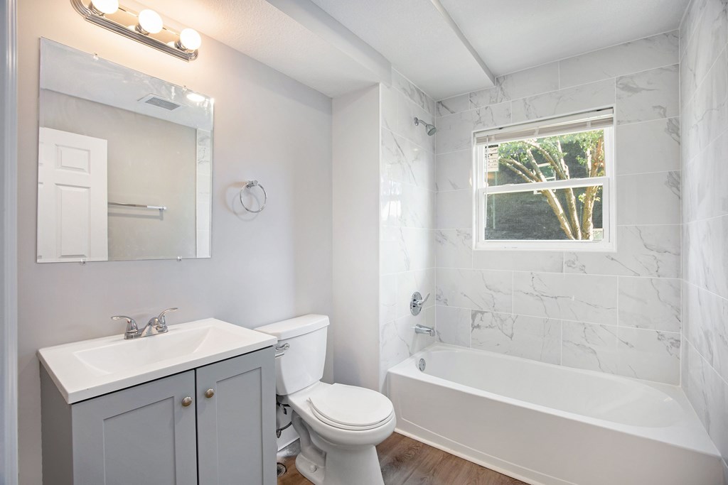A white bathroom with a toilet, sink, and bathtub.at Palisades Apartments, Kansas City, MO 64133