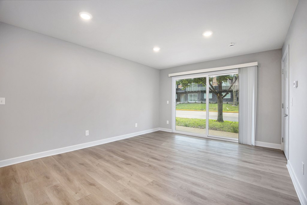 A room with wooden flooring and a sliding glass door leading to a balcony.at Palisades Apartments, Kansas City, MO 64133