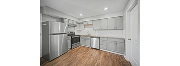 A kitchen with a wooden floor and stainless steel appliances.