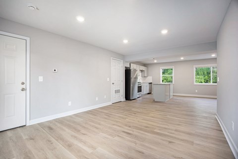 A spacious room with wooden flooring and white walls.