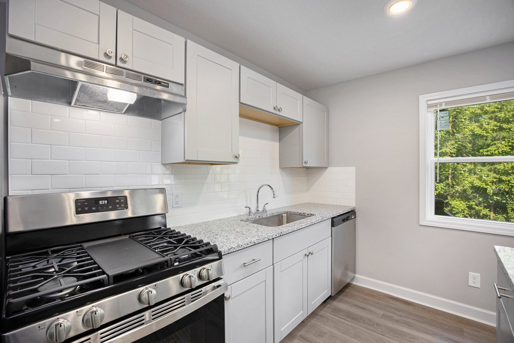 A kitchen with a stove top oven and white cabinets.at Palisades Apartments, Missouri, 64133